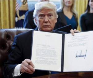 WASHINGTON, DC - JANUARY 23: (AFP OUT) U.S. President Donald Trump shows the Executive Order withdrawing the US from the Trans-Pacific Partnership (TPP) after signing it in the Oval Office of the White House in Washington, DC on Monday, January 23, 2017. The other two Executive Orders concerned a US Government hiring freeze for all departments but the military, and 'Mexico City' which bans federal funding of abortions overseas. (Photo by Ron Sachs - Pool/Getty Images)