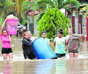 Un grupo de mujeres en la colonia Jerusalén, de La Lima, se enfrentan al riesgo de caminar con el agua arriba de las rodillas para sacar sus pertenencias.