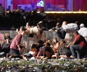 LAS VEGAS, NV - OCTOBER 01: People scramble for shelter at the Route 91 Harvest country music festival after apparent gun fire was heard on October 1, 2017 in Las Vegas, Nevada. A gunman has opened fire on a music festival in Las Vegas, leaving at least 20 people dead and more than 100 injured. Police have confirmed that one suspect has been shot. The investigation is ongoing. David Becker/Getty Images/AFP