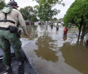 El agente de la Patrulla Fronteriza estadounidense Steven Blackburn, a la izquierda, comprueba si las personas que vadean en el agua necesitan ayuda durante una búsqueda de una operación de rescate en un vecindario inundado por las inundaciones de la tormenta tropical Harvey en Houston, Texas. Agencia AFP.