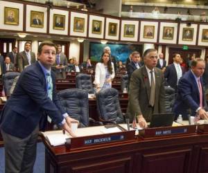 El representante republicano Jason Brodeur, izquierda, observa el tablero de votaciones sobre la propuesta de ley de seguridad escolar mientras emite su sufragio en Tallahassee, Florida, el miércoles 7 de marzo de 2018.