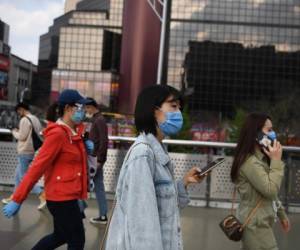 Beijing: la gente usa máscaras faciales en medio de las preocupaciones sobre el coronavirus COVID-19 mientras caminan afuera de un centro comercial en Beijing el 17 de abril de 2020. La economía de China se contrajo por primera vez en décadas el último trimestre cuando el coronavirus paralizó al país, en un histórico golpe a la promesa del Partido Comunista de prosperidad continua a cambio de un poder político incuestionable. / AFP / GREG BAKER