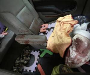 Prendas y juguetes ensangrentados vistos en el interior de una camioneta baleada en la que viajaban miembros de la familia LeBarón, estacionada en una carretera de tierra en Bavispe, cerca de la frontera entre los estados mexicanos de Sonora y Chihuahua, el 6 de noviembre de 2019. (AP Foto/Christian Chávez).