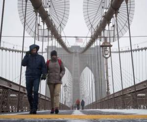 NEW YORK, NY - MARCH 14: People brave the wind and wintry mix as they walk across the Brooklyn Bridge, March 14, 2017 in New York City. New York City was mostly spared from the winter storm that hit the northeast. Drew Angerer/Getty Images/AFP