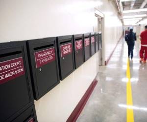 Buzones para diferentes departamentos en un pasillo mientras varios detenidos caminan por el Centro de Detención Stewart, el viernes 15 de noviembre de 2019 en Lumpkin, Georgia. La población rural se encuentra unos 225 kilómetros (140 millas) al suroeste de Atlanta, cerca de la frontera con Alabama. Los 1.172 habitantes de la localidad se ven superados por los aproximadamente 1.650 detenidos que había a finales de noviembre en el centro, según el Servicio de Control de Inmigración y Aduanas de Estados Unidos (ICE por sus siglas en inglés). (AP Foto/David Goldman)