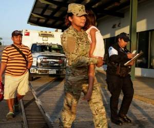 Jose González, izquierda, sigue a su hija de cinco años, cargada por una oficial de policía, tras dejar un hospital en Santiago, Panamá, el jueves 16 de enero de 2020. La esposa de González y cinco de sus hijos están entre las siete personas que habrían sido asesinadas por una secta. (AP Foto/Arnulfo Franco)