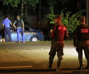 Elementos de la Dirección Policial de Investigaciones (DPI) y Policía Militar observan el vehículo en el que se conducían las cinco víctimas de masacre en el bulevar del Este de San Pedro Sula.