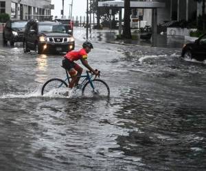Un ciclista recorre la calle inundada durante fuertes lluvias y viento causados por la tormenta tropical Eta, al sur de Florida. Foto: AFP