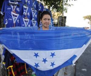 Michelle de Molina sostiene con sus manos el pabellón nacional, quien comercializa las camisas de la bicolor a 12 dólares, es decir unos 274 lempiras.