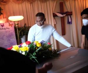 Kenneth Cattenhead, director ejecutivo de la funeraria The Family, ayuda a transportar un féretro el jueves 30 de abril de 2020 hasta una carroza en Newark, Nueva Jersey. Las familias han tenido que honrar a sus muertos a distancia y en pequeños grupos durante los tiempos actuales de distanciamiento social. (AP Foto/Seth Wenig)