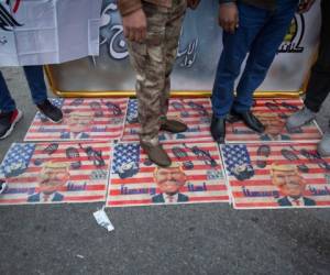 Los dolientes pisan una bandera estadounidense con fotos del presidente Trump mientras esperan el funeral del principal general de Irán, Qassem Soleimani, y Abu Mahdi al-Muhandis, subcomandante de las milicias respaldadas por Irán en Irak, conocidas como las Fuerzas de Movilización Popular, en Bagdad, Irak. Sábado 4 de enero de 2020. Miles de personas que cantaban 'Estados Unidos es el gran Satanás' marcharon en una procesión fúnebre el sábado a través de Bagdad por el principal general iraní y los líderes militantes iraquíes, que fueron asesinados en un ataque aéreo estadounidense. (Foto AP / Nasser Nasser)
