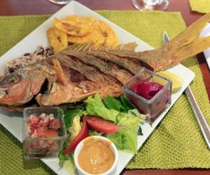 El pescado frito es disfrutado de diversas formas en Honduras, pero la consentida es con tajadas de plátano y chismol o encurtido.