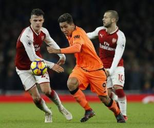 El centrocampista brasileño del Liverpool Roberto Firmino (C) compite con el mediocampista suizo del Arsenal Granit Xhaka (L) durante el partido de fútbol de la Premier League inglesa entre el Arsenal y el Liverpool en el Emirates Stadium de Londres. Agencia AFP.