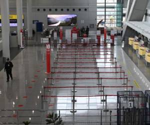 A security officer (L) walks past empty check-in counters at the airport in Manila on August 4, 2020, after all domestic flights were cancelled following new restrictions to combat the COVID-19 coronavirus outbreak. - More than 27 million people -- a quarter of the Philippine population -- were give 24-hours notice of the new restrictions that have shuttered many businesses, halted public transport and grounded flights in the capital and four surrounding provinces as the government battles to rein in the virus. (Photo by Ted ALJIBE / AFP)