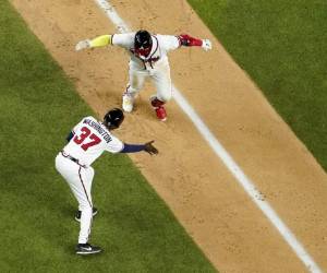 El dominicano Marcell Ozuna, de los Bravos de Atlanta, festeja su jonrón con el coach de tercera base Ron Washington en la séptima entrada del 4to partido contra los Dodgers de Los Ángeles, en la serie por el Campeonato de la Liga Nacional en Arlington, Texas, el jueves 15 de octubre de 2020. Foto: AP