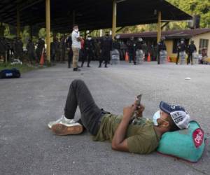 Un migrante hondureño descansa ante un bloqueo de carretera impuesto por las fuerzas de seguridad en Poptun, Guatemala, el 2 de octubre de 2020. Foto: AP