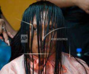 Una mujer permanece sentada mientras un estudiante de peluquería le corta el cabello que resultó quemado tras la erupción del Volcán de Fuego en un albergue en Escuintla, Guatemala, el miércoles 6 de junio de 2018.