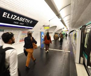 Los viajeros pasan junto a un letrero en la estación de metro parisina “George V”, que se reemplaza temporalmente con un cartel que dice “Elizabeth II 1926-2022”.