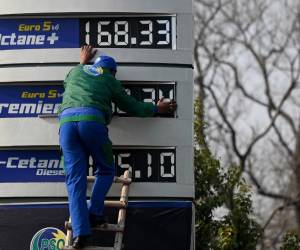 Un empleado de una gasolinera actualiza la última lista de precios de combustible después de un aumento en los precios de los productos derivados del petróleo.