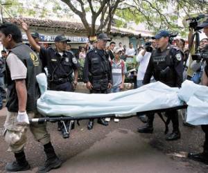 Un grupo de agentes de la Policía ayuda a empleados de Medicina Forense a retirar el cuerpo de Julián Arístides González de la escena del crimen.