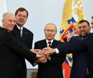 El presidente Vladimir Putin (centro) junta sus manos con las de los dirigentes de las cuatro regiones de Ucrania tras firmar los tratados de anexión a Rusia, el 30 de septiembre de 2022 en Moscú.