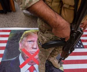 Basora, Iraq: un miembro de la red paramilitar Hashed al-Shaabi de Iraq se encuentra en una bandera estadounidense durante una procesión fúnebre simbólica para la red de diputados Abu Mahdi al-Muhandis en la ciudad sureña de Basora, el 4 de enero de 2020. Decenas de miles de Los iraquíes lloraron a al-Muhandis y al mayor general iraní Qasem Soleimani junto con otros ocho muertos en un ataque con aviones no tripulados de Estados Unidos ayer que despertó los temores de una guerra de poder regional entre Washington y Teherán. / AFP / Hussein FALEH