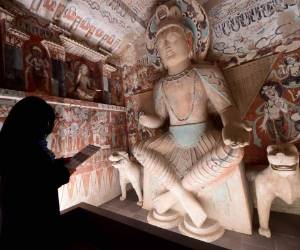 Una mujer lee la historia de una enorme escultura de Buda que se erige en una réplica de las Grutas de Mogao en el Centro Getty de Los ángeles.