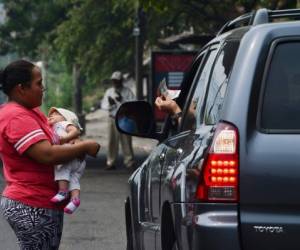 Cintia Suyapa, con su hijo en brazos, pide para comer en una calle de Tegucigalpa.