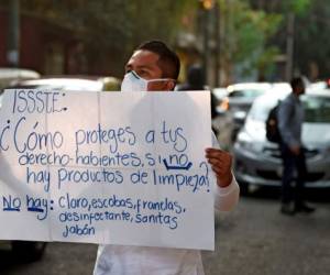 Ciudad de México, México: Un trabajador de salud del Hospital General de Tacuba sostiene un letrero que dice '¿Cómo protege a los titulares de derechos si no hay productos de limpieza? No hay: cloro, escobas, paños de limpieza, desinfectantes, papel de limpieza, jabón ”durante una demostración de la falta de material médico para atender a los pacientes con COVID-9, en la Ciudad de México el 21 de abril de 2020. / AFP / ALFREDO ESTRELLA