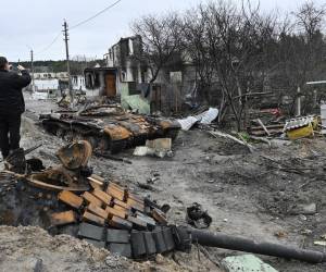 Un hombre toma una foto de los restos de un tanque junto a las casas residenciales destruidas en el pueblo de Zalissya, al noreste de Kiev.
