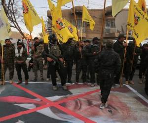 Miembros de la fuerza paramilitar Hashed al-Shaabi caminan sobre un retrato del presidente estadounidense Donald Trump mientras sostienen una reunión de condolencias tras los asesinatos del comandante iraní Qassem Soleimani y el comandante paramilitar iraquí Abu Mahdi Al-Muhandis, el 6 de enero de 2020 en Karrada en El centro de Bagdad. (Foto por AHMAD AL-RUBAYE / AFP)