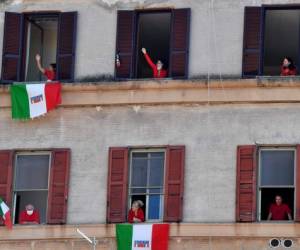 Los residentes con banderas italianas en el distrito de Garbatella de Roma participan el 25 de abril de 2020 en un flashmob del 'Día de la Liberación' con personas cantando la canción partizan italiana 'Bella Ciao' desde su ventana o balcón, durante el cierre del país destinado a frenar la propagación de la infección por COVID-19, causada por el nuevo coronavirus. (Foto por Tiziana FABI / AFP)
