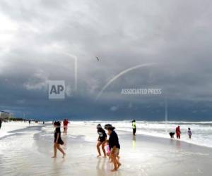 Bañistas caminan en la zona de Okaloosa Island en Fort Walton Beach, Florida, el lunes 28 de mayo de 2018, antes de que la tormenta subtropical Alberto tocara tierra en el noroeste del estado.