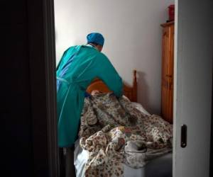 Madrid: TOPSHOT - El médico venezolano Diego Padrón acuesta a un residente aislado en un hogar de ancianos para ancianos en Madrid el 24 de abril de 2020. ¿Qué errores provocaron tantas muertes? España comienza a investigar las tragedias detrás de las puertas cerradas de sus casas de retiro, donde miles de muertes se atribuyen al coronavirus. / AFP / OSCAR DEL POZO