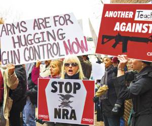 Protesters marching with the social activist group CREDO along with other concerned citizens descend on the offices of the NRA's (National Rifle Association)Capitol Hill lobbiest's office demanding the pro-gun lobby stand down in reaction to the shooting at Sandy Hook Elementary School December 17, 2012, in Washington, DC. A leading Democratic senator launched a bid Sunday to ban assault weapons in the wake of the latest deadly US school shooting, announcing that she will put a bill before Congress on January 3.Dianne Feinstein, the influential chair of the Senate Intelligence Committee, said she believed President Barack Obama would support her legislation, also aimed at outlawing magazines carrying more than 10 bullets. AFP Photo/Paul J. Richards