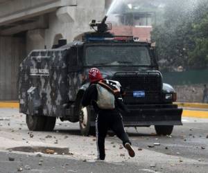 Un manifestante enfrenta la tanqueta de agua que llega para frenar la protesta. (Foto: AFP/ El Heraldo Honduras/ Noticias Honduras hoy)