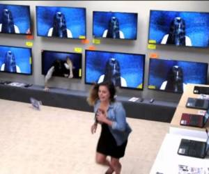 Una mujer sale corriendo al ver a la niña salir del televisor ubicado en la tienda.