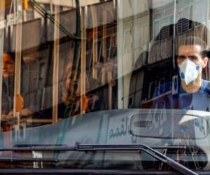 A bus driver wearing a protective mask as a precaution against COVID-19 coronavirus disease operates a bus in Iran's capital Tehran on March 15, 2020. (Photo by STRINGER / AFP)