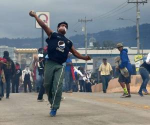 Un hombre lanza piedras durante la manifestación en espera de resultados que incluyan todas las actas. (Foto: AFP/ El Heraldo Honduras/ Noticias Honduras hoy)