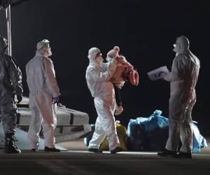 Ankara: una persona sostiene a un niño mientras los pasajeros toman sus maletas mientras desembarcan de un avión de carga turco en el aeropuerto militar de Etimesgut en Ankara el 1 de febrero de 2020, después de ser repatriados desde la ciudad china de Wuhan, el epicentro del nuevo brote de coronavirus. / AFP / Adem ALTAN