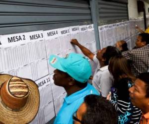 Colombianos buscan su número de identificación en el registro electoral antes de votar en el consulado de Colombia en Caracas, Venezuela, para el referéndum sobre la conveniencia de ratificar un acuerdo histórico de paz para poner fin a la guerra de 52 años de Colombia entre el estado y los rebeldes de las FARC. Foto: AFP