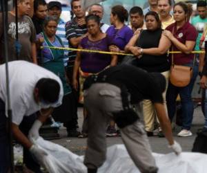 Investigadores policiales trabajan en la escena del crimen donde cinco vendedores del mercado y un guardia de seguridad privado fueron asesinados durante una supuesta confrontación de pandillas en San Salvador. Foto: Agencia AFP.