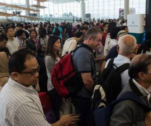 Las calles desiertas de Hong Kong empezaron poco a poco a reanudar la normalidad el martes, con los autobuses y los trenos funcionando de nuevo, aunque en el aeropuerto internacional cientos de pasajeros seguían bloqueados.