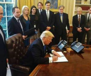 US President Donald Trump holds an executive memorandum on defeating the Islamic State in Iraq and Syria after signing it in the Oval Office of the White House on January 28, 2017, in Washington, DC. Counselor to the President Kellyanne Conway (3rd L) and White House Chief of Staff Reince Priebus (2nd L) joined Trump. / AFP / MANDEL NGAN