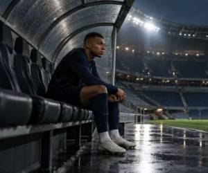 Kylian Mbappé sentado en el banquillo de un estadio de fútbol vacío