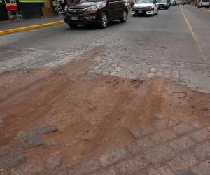 Los conductores de carros y de motocicletas deben esquivar los enormes agujeros de la calle.