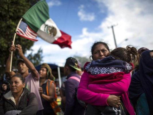 La migrante hondureña Leticia Núñez carga a su hija Mailyn mientras forma parte de un pequeño grupo de migrantes que intenta abrirse paso rumbo a Estados Unidos. Foto: AP.