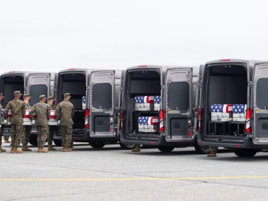 Una caja de transferencia cubierta con una bandera con los restos de un miembro del servicio caído se coloca dentro de un vehículo de transferencia. Foto: AFP