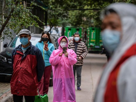 This photo taken on March 16, 2020 shows residents wearing face masks queueing to get their order of foods and vegetables in Wuhan, China's central Hubei province. - China reported on March 17 just one new domestic coronavirus infection but found 20 more cases imported from abroad, threatening to spoil its progress against the disease. (Photo by STR / AFP) / China OUT