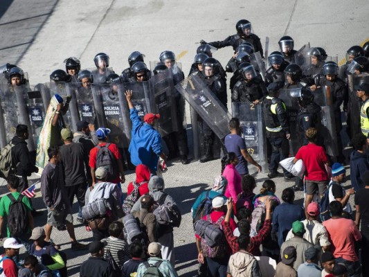 Fotos del momento en el que migrantes de la caravana saltaron valla fronteriza de Estados Unidos, pero fueron detenidos con gases lacrimógenos